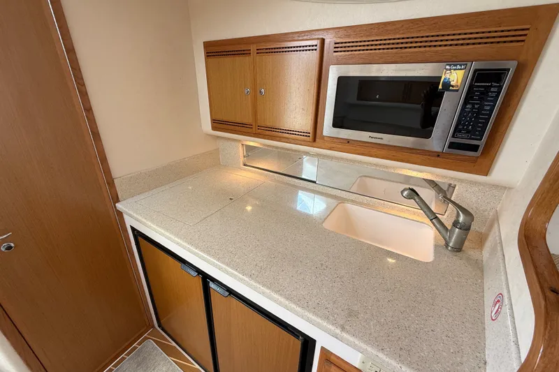 Slide: The Image of Compact kitchen area in a 2007 Cabo 32 Express boat with microwave and sink. - 64