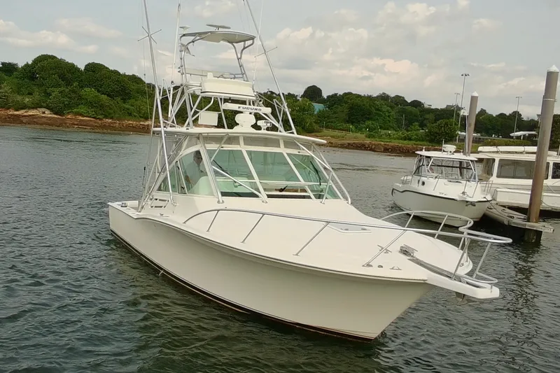 Slide: The Image of 2007 Cabo 32 Express boat docked in a serene marina setting. - 2