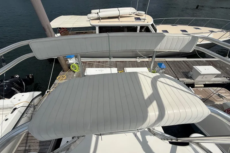 Slide: The Image of 2007 Cabo 32 Express boat seating area at dock, featuring white cushioned seats. - 57