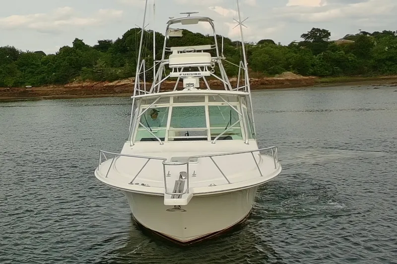 Slide: The Image of 2007 Cabo 32 Express boat on calm water near a wooded shoreline. - 1