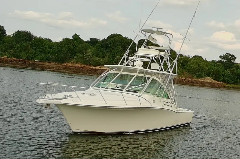 The Image of 2007 Cabo 32 Express boat on calm water with lush green shoreline. - 0
