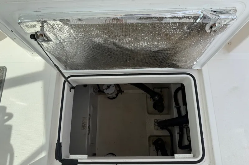 Slide: The Image of An open storage compartment on a 2007 Cabo 32 Express boat, with visible pipes and insulation. - 26