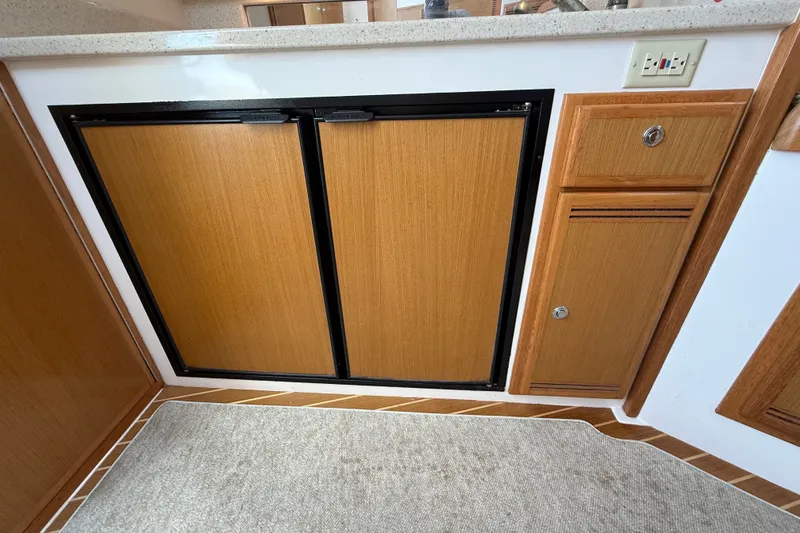Slide: The Image of 2007 Cabo 32 Express interior with wooden cabinetry and dual-door refrigerator. - 66
