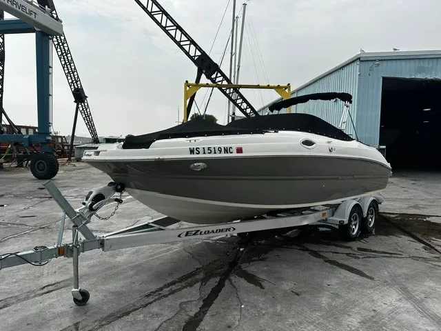 The Image of A 2021 Stingray 231 boat on a trailer in a shipyard area. - 0