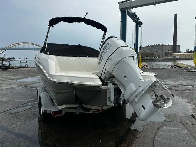 Slide: The Image of 2021 Stingray 231 boat with black canopy and Suzuki outboard motor, on a trailer. - 2