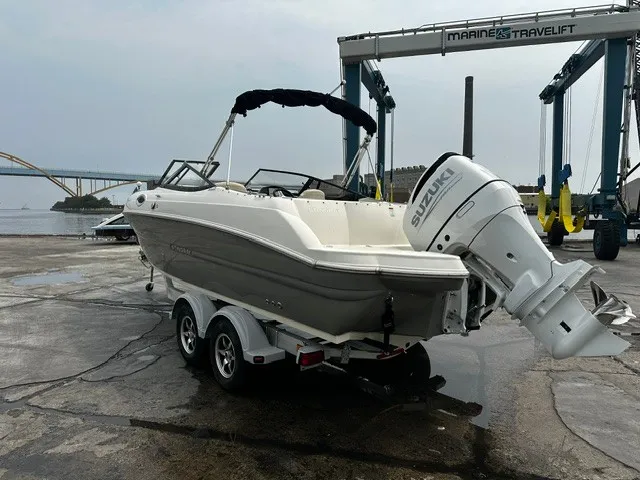 Slide: The Image of A 2021 Stingray 231 boat on a trailer, featuring a Suzuki outboard motor, is parked at a dock. - 26