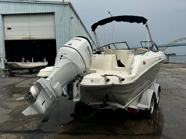 Slide: The Image of A white motorboat with a large outboard engine sits on a trailer outside a warehouse. - 25