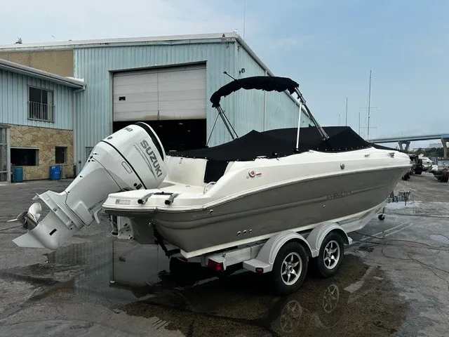 Slide: The Image of A 2021 Stingray 231 boat with a Suzuki outboard motor, on a trailer in front of a warehouse. - 5