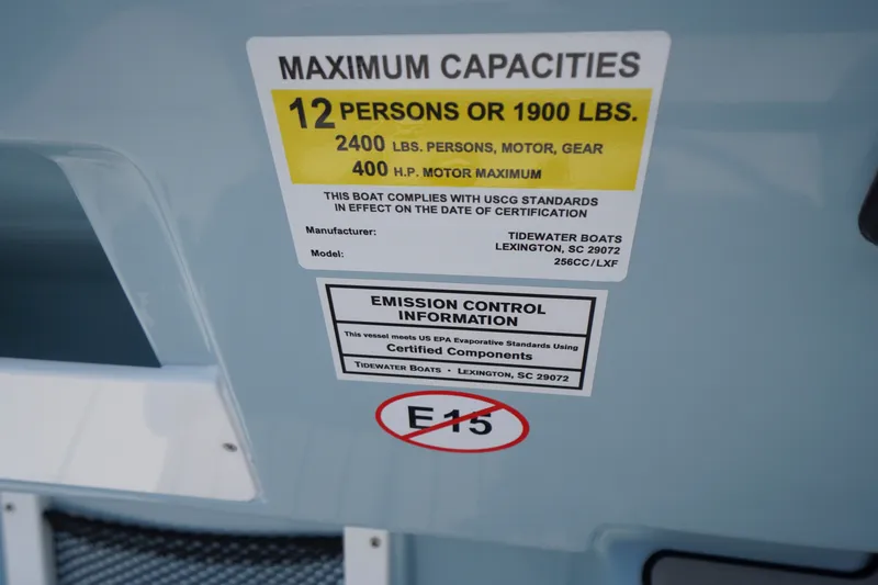 Slide: The Image of 2027 Tidewater 256 LXF boat capacity label, 12 persons or 1900 lbs, emission control info. - 37