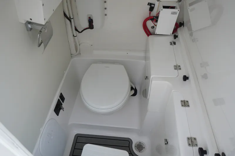 Slide: The Image of Interior of 2027 Tidewater 256 LXF boat featuring a compact marine toilet setup. - 27