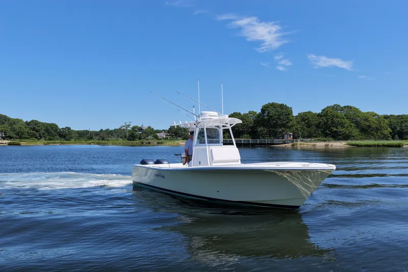Slide: The Image of 2007 Regulator 29 Forward Seating boat cruising on a serene lake under a clear blue sky. - 21