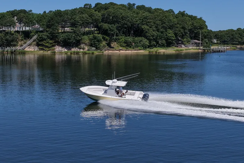 Slide: The Image of 2007 Regulator 29 Forward Seating boat cruising on a serene lake with lush green shoreline. - 30