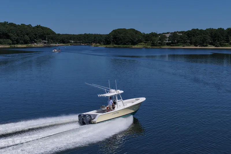 Slide: The Image of 2007 Regulator 29 Forward Seating boat cruising on a serene lake under clear blue skies. - 27