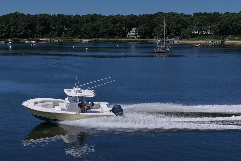 Slide: The Image of 2007 Regulator 29 Forward Seating boat cruising on a serene lake with lush forest backdrop. - 35