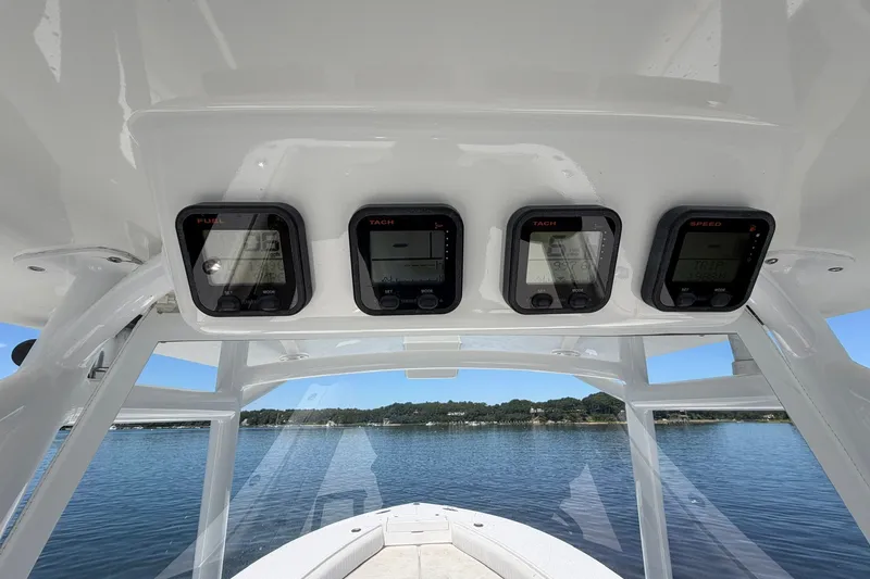 Slide: The Image of 2007 Regulator 29 Forward Seating boat dashboard with gauges, overlooking calm water and distant shoreline. - 57