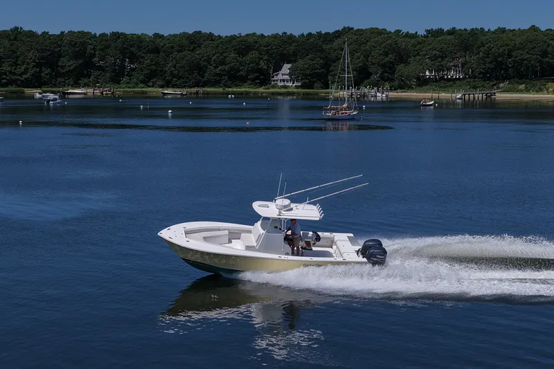 Slide: The Image of 2007 Regulator 29 Forward Seating boat cruising on a serene lake with lush forest backdrop. - 34