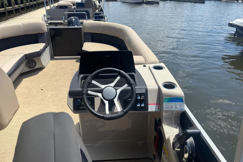 Slide: The Image of 2024 Harris Cruiser 230 boat interior with steering wheel and seating on the water. - 6