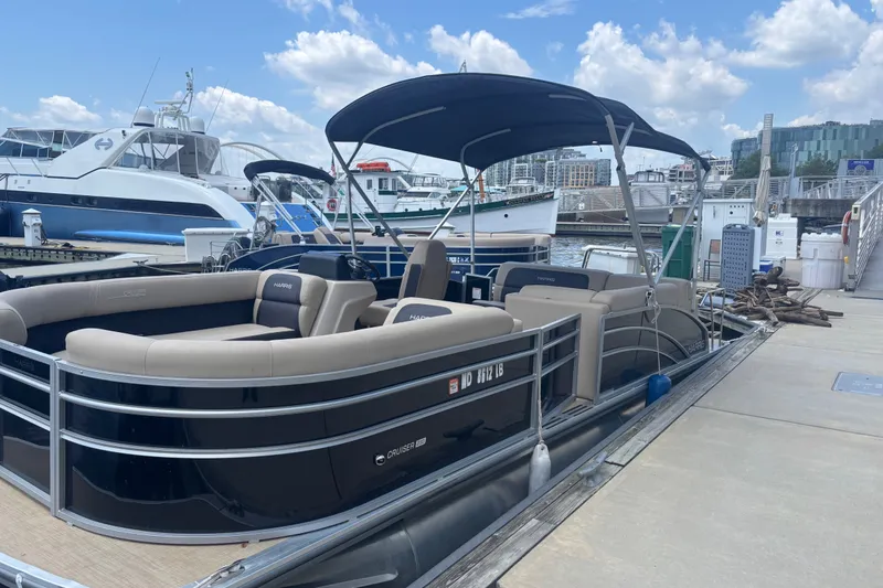 Slide: The Image of 2024 Harris Cruiser 230 pontoon boat docked at marina under blue sky. - 4
