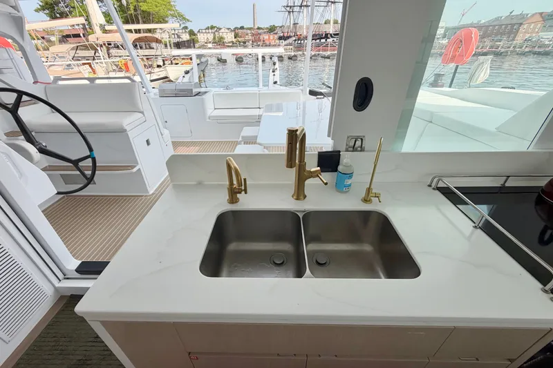 Slide: The Image of Modern yacht kitchen with dual sinks, gold faucets, and marina view. Balance 526, 2025 model. - 105