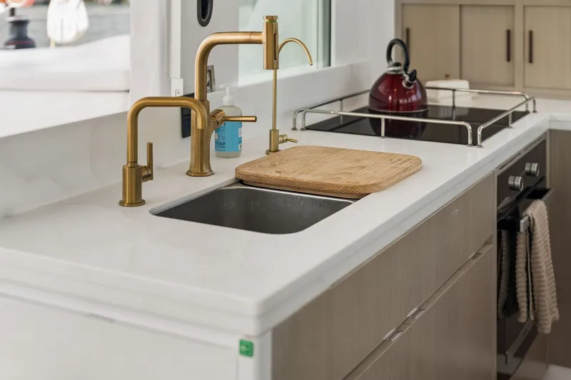 Slide: The Image of Modern kitchen sink with gold faucet, cutting board, and red kettle on stove. Balance 526, 2025. - 41