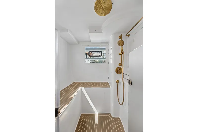 Slide: The Image of Luxurious yacht shower with gold fixtures, teak flooring, and a porthole window. Balance 526, 2025. - 65