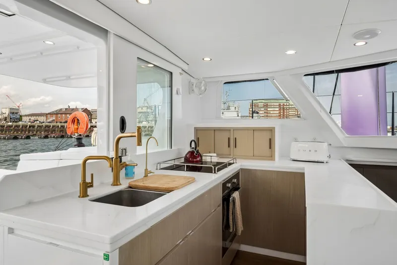 Slide: The Image of Modern yacht kitchen interior with sleek design, featuring gold fixtures and waterfront view. Balance 526, 2025. - 40