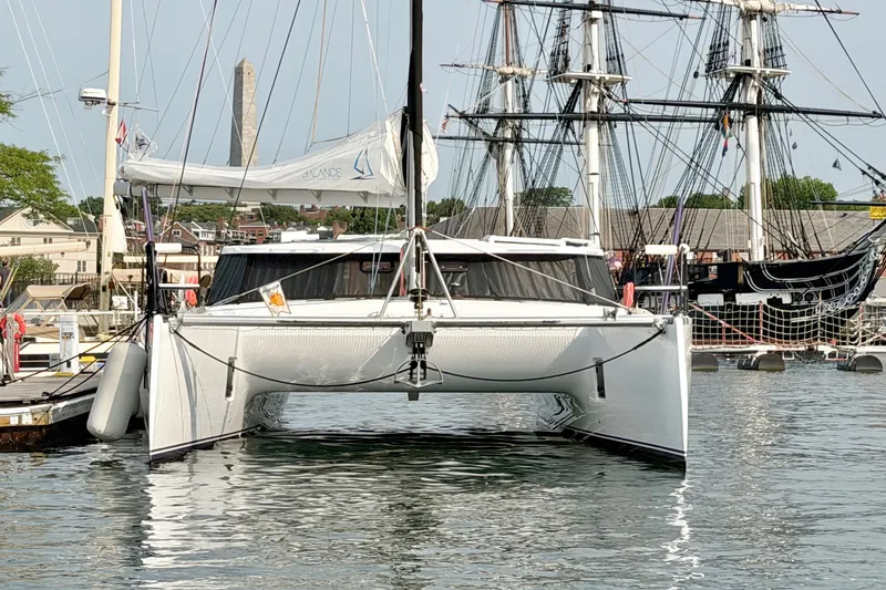 Slide: The Image of Modern Balance 526 catamaran docked in harbor, 2025 model, with historic ships in background. - 141