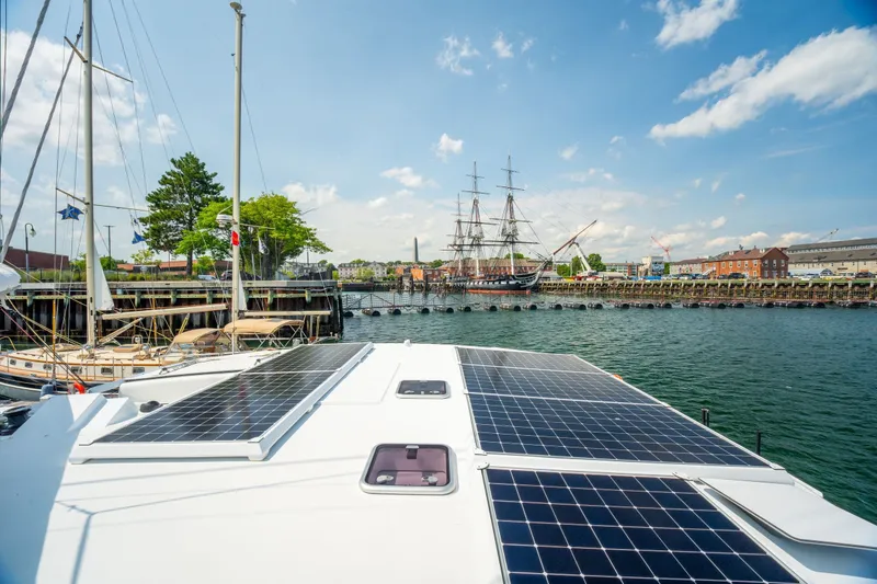 Slide: The Image of Modern Balance 526 yacht with solar panels docked near historic ship, sunny day, 2025 model. - 14