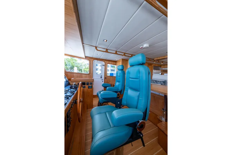 Slide: The Image of Pilothouse of 2026 Kadey-Krogen 60 Open with blue captain chairs and wooden interior. - 23