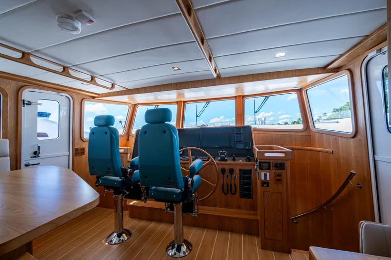 Slide: The Image of Pilothouse interior of 2026 Kadey-Krogen 60 Open yacht with blue chairs and wooden finish. - 16