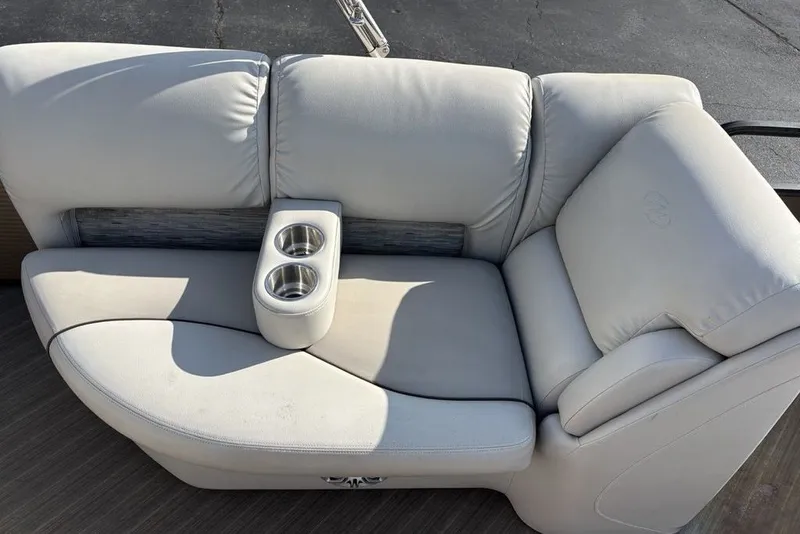 Slide: The Image of 2015 Manitou 25 SHP SES boat seating with dual cup holders, featuring light gray upholstery. - 17