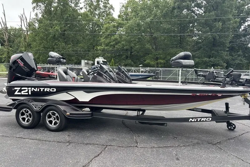Slide: The Image of 2021 Nitro Z21 boat on trailer, parked outdoors with trees in background. - 42