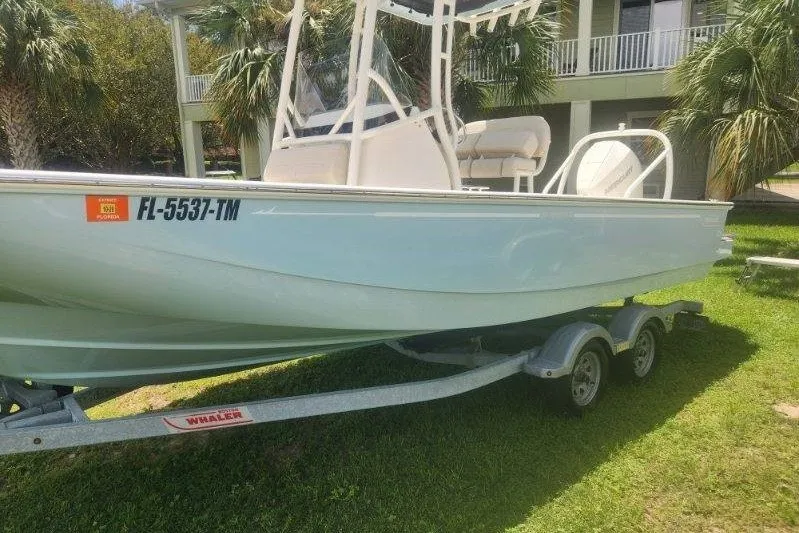 Slide: The Image of 2023 Boston Whaler 210 Montauk boat on trailer, parked on grass. - 1
