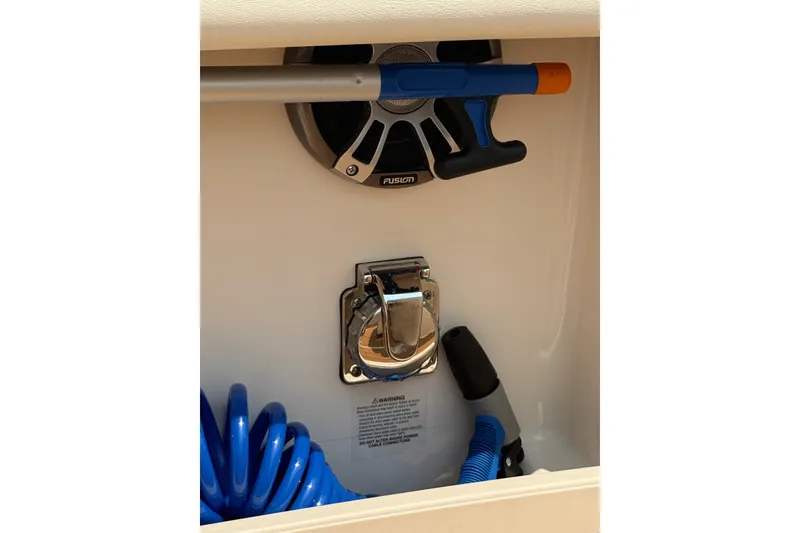 Slide: The Image of Storage compartment in 2024 Grady-White Freedom 285 boat with coiled hose and speaker. - 23