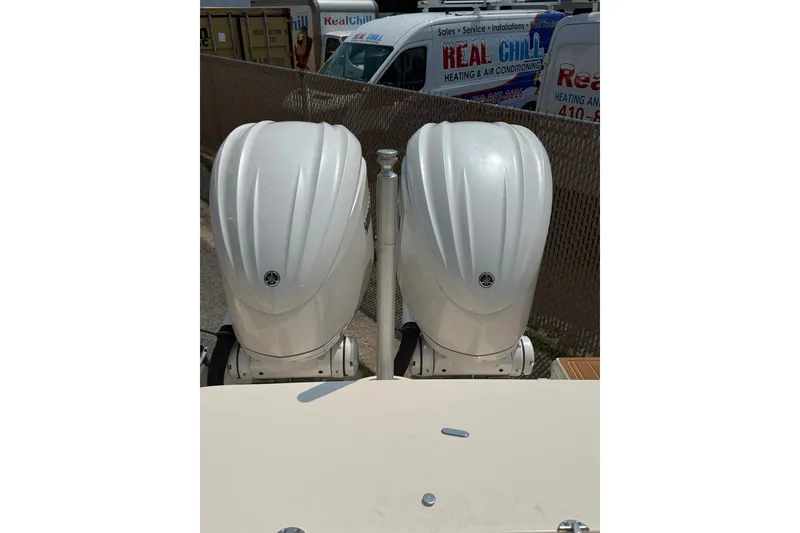Slide: The Image of Twin outboard engines on a 2024 Grady-White Freedom 285 boat, parked near service vans. - 4