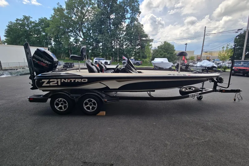 Slide: The Image of 2016 Nitro Z21 boat on trailer, parked outdoors with trees and cloudy sky background. - 3
