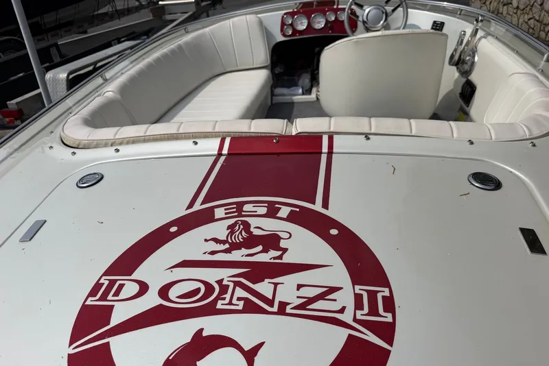 Slide: The Image of 1990 Donzi Sweet 16 boat interior with red logo and white seating. - 2