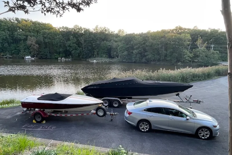 Slide: The Image of 1990 Donzi Sweet 16 boat for sale, parked near a serene lake with a car. - 23