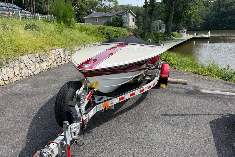 Slide: The Image of 1990 Donzi Sweet 16 boat on trailer near a lakeside dock. - 21