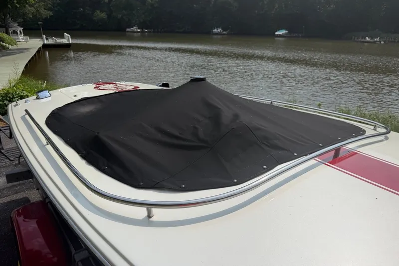 Slide: The Image of 1990 Donzi Sweet 16 boat with black cover, docked by a serene lake. - 25