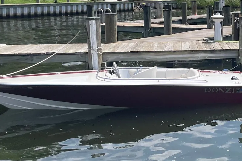 The Image of 1990 Donzi Sweet 16 boat docked on calm water, showcasing sleek design and classic style. - 0