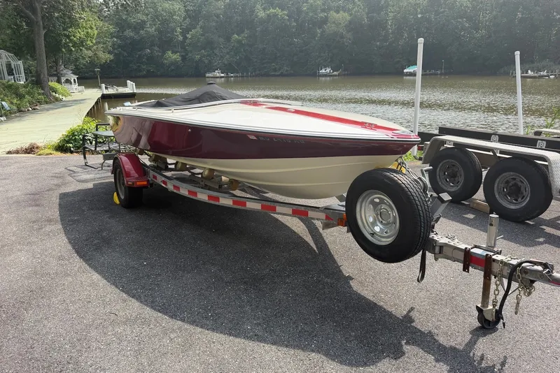 Slide: The Image of 1990 Donzi Sweet 16 boat on trailer by a lakeside, surrounded by trees. - 26