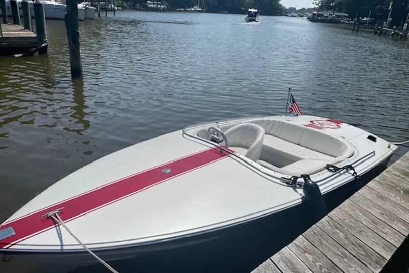 Slide: The Image of 1990 Donzi Sweet 16 boat docked on a calm lake with American flag. - 1