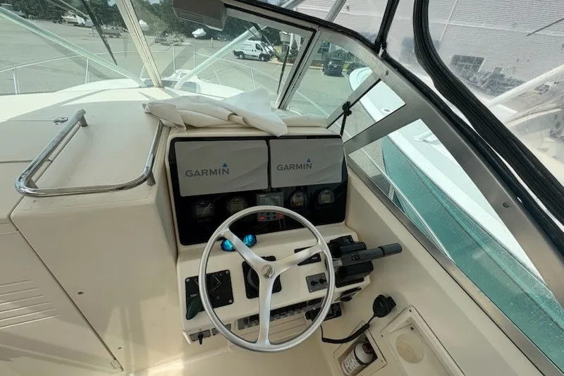 Slide: The Image of 1999 Pursuit 2870 Walkaround boat helm with Garmin navigation displays and steering wheel. - 16