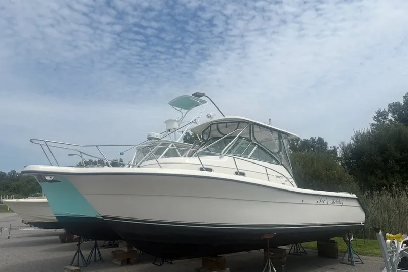 The Image of 1999 Pursuit 2870 Walkaround boat on stands under a cloudy sky. - 0