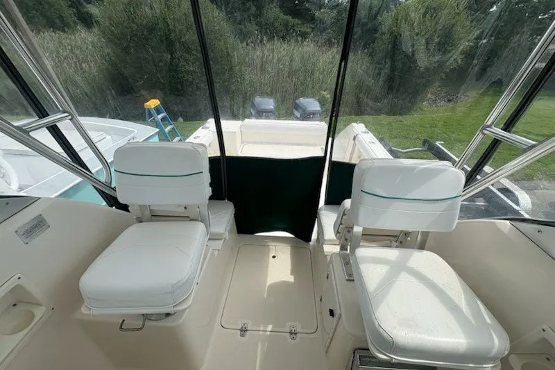 Slide: The Image of 1999 Pursuit 2870 Walkaround boat interior with two white seats and clear canopy. - 14