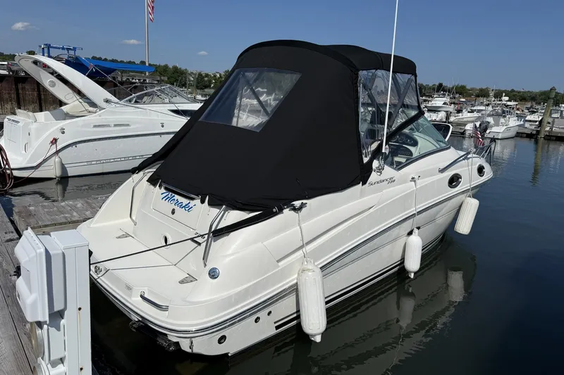 Slide: The Image of 2009 Sea Ray 230 Sundancer docked at marina, featuring black canopy and white hull. - 1