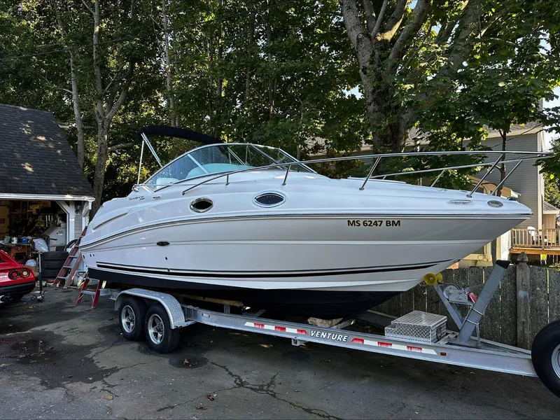 Slide: The Image of A white 2009 Sea Ray 230 Sundancer boat is on a trailer in a yard. - 2