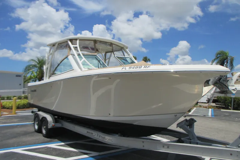 Slide: The Image of 2017 Sailfish 275 DC boat on trailer under a clear blue sky. - 2