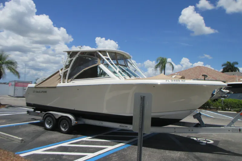 Slide: The Image of 2017 Sailfish 275 DC boat on trailer under a sunny sky. - 3
